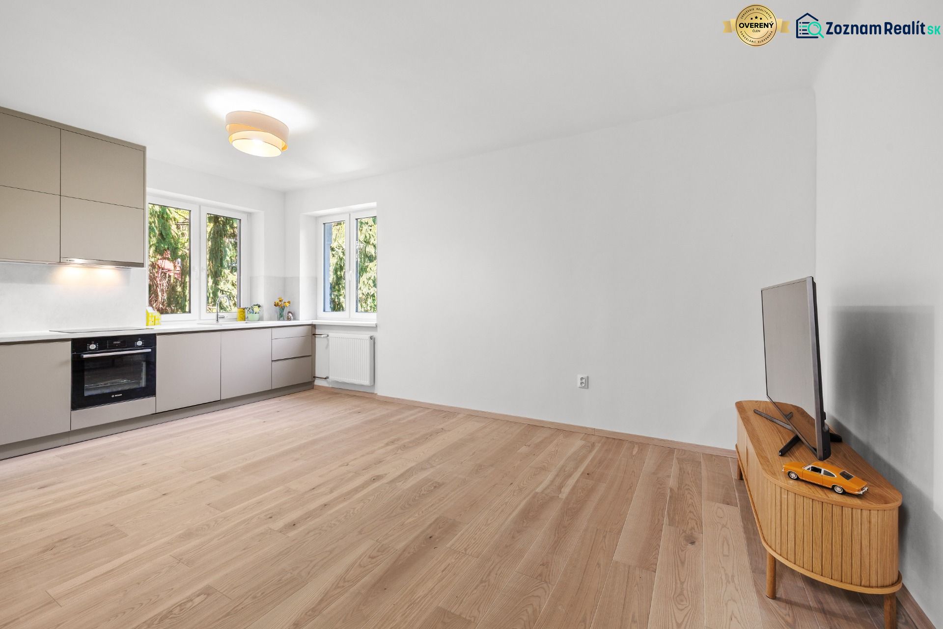 A spacious kitchen in a 3-room apartment with a wooden decor floor and minimalist furniture.