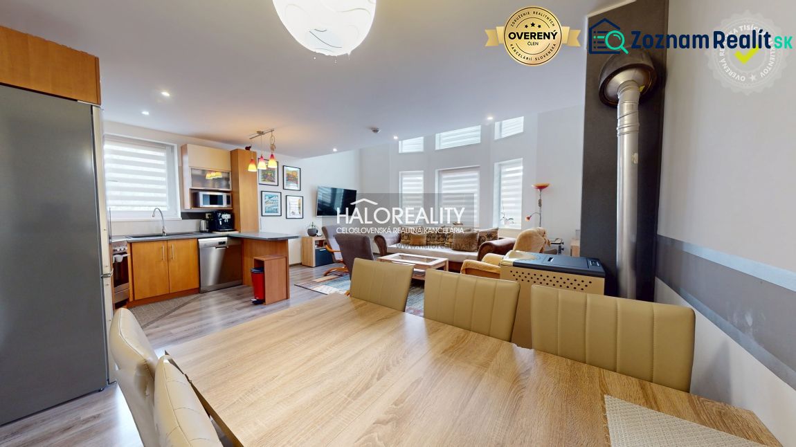 A spacious kitchen in a family house with a wood-patterned floor and modern furniture.