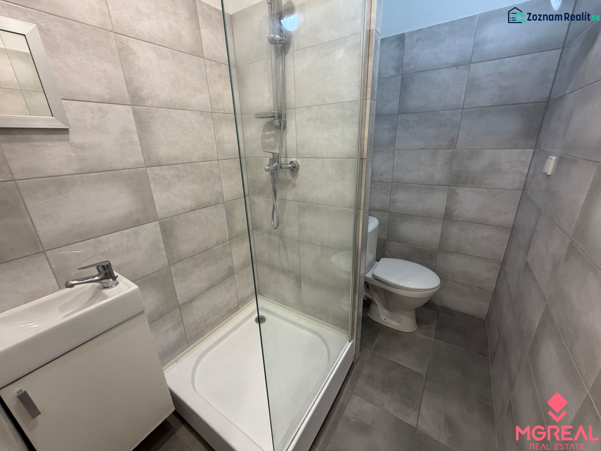 A bathroom in a studio apartment with a toilet, shower, and sink.