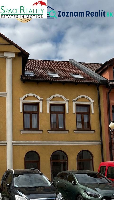 A building in Topoľčany with a historical facade and parked cars in front of it.
