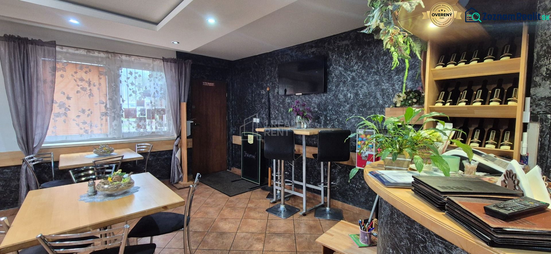Interior of commercial premises with a bar, tables, and decorative plants.