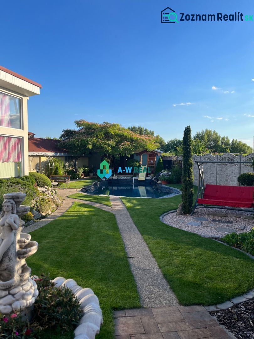 The garden of a family house in Orechová Potôň with a swimming pool, lawns, and a statue.