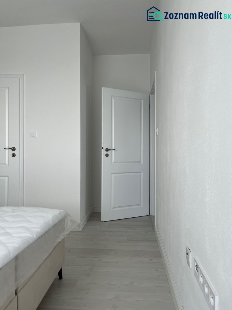 A bedroom with white walls and a wooden decor floor in a three-room apartment.