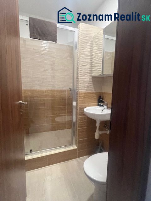 A bathroom in a building with a shower, a sink, and a floor with a wooden decor.