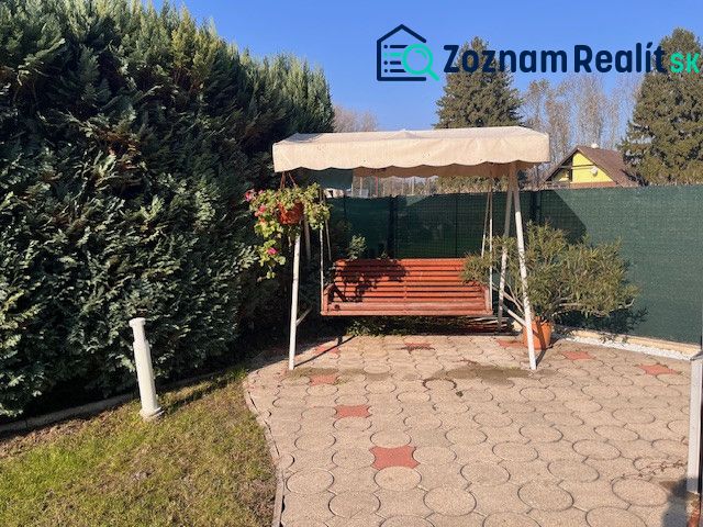 The garden of a family house in Gabčíkovo with a swing, built into a tiled terrace.