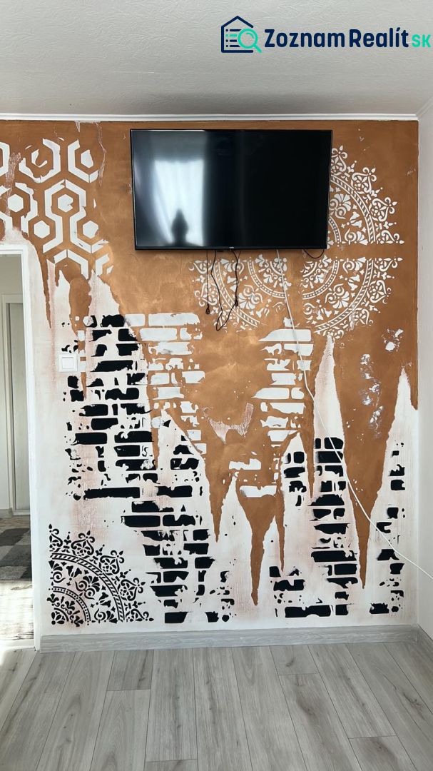 A television on the wall with artistic patterns, a floor with wooden decor in a family house.