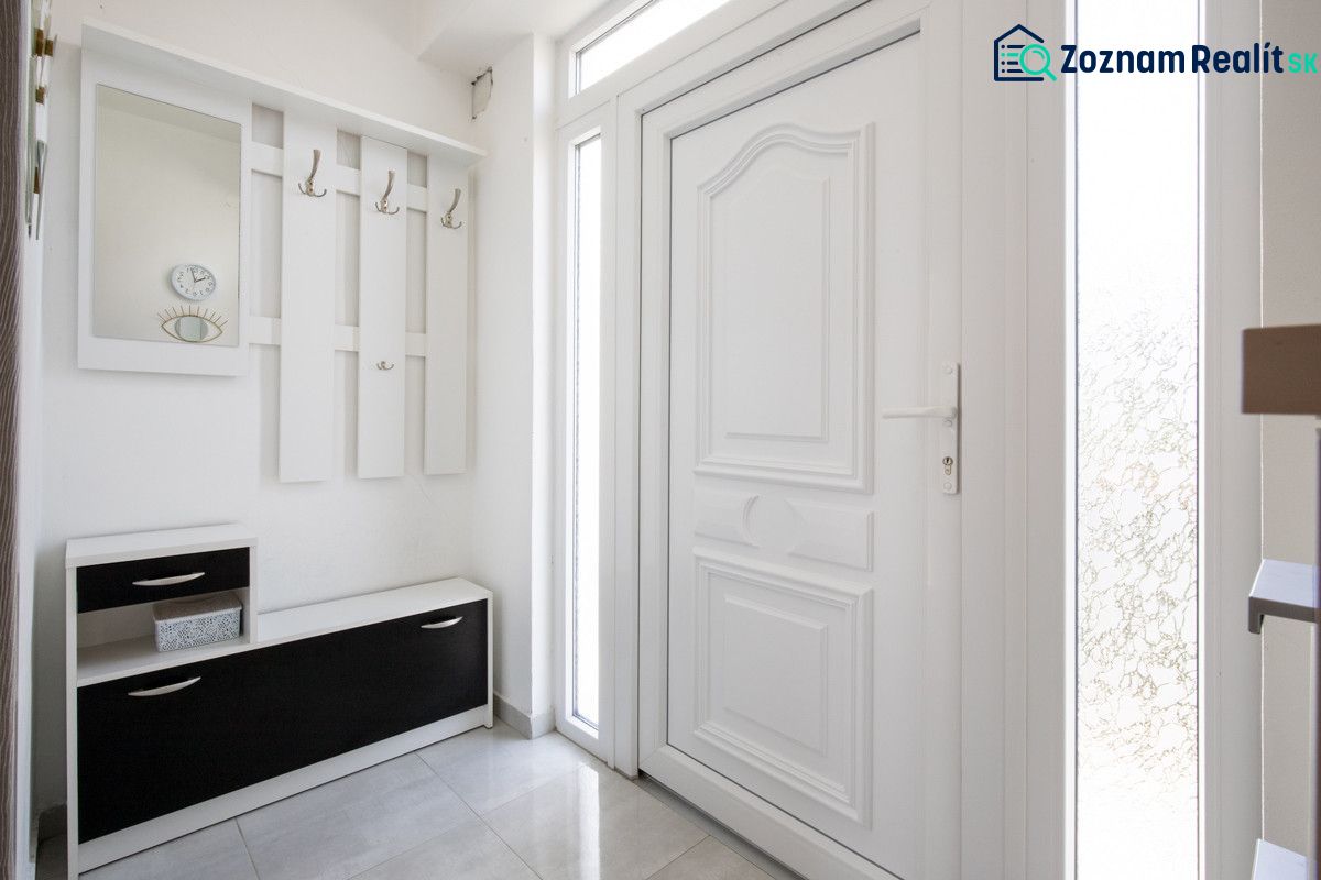 White hallway in a family house with a coat rack, storage space, and a mirror.