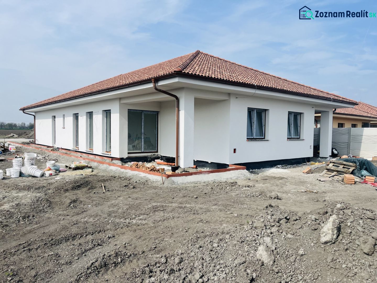 A family house in Michal na Ostrove under construction with a white facade and a hipped roof.