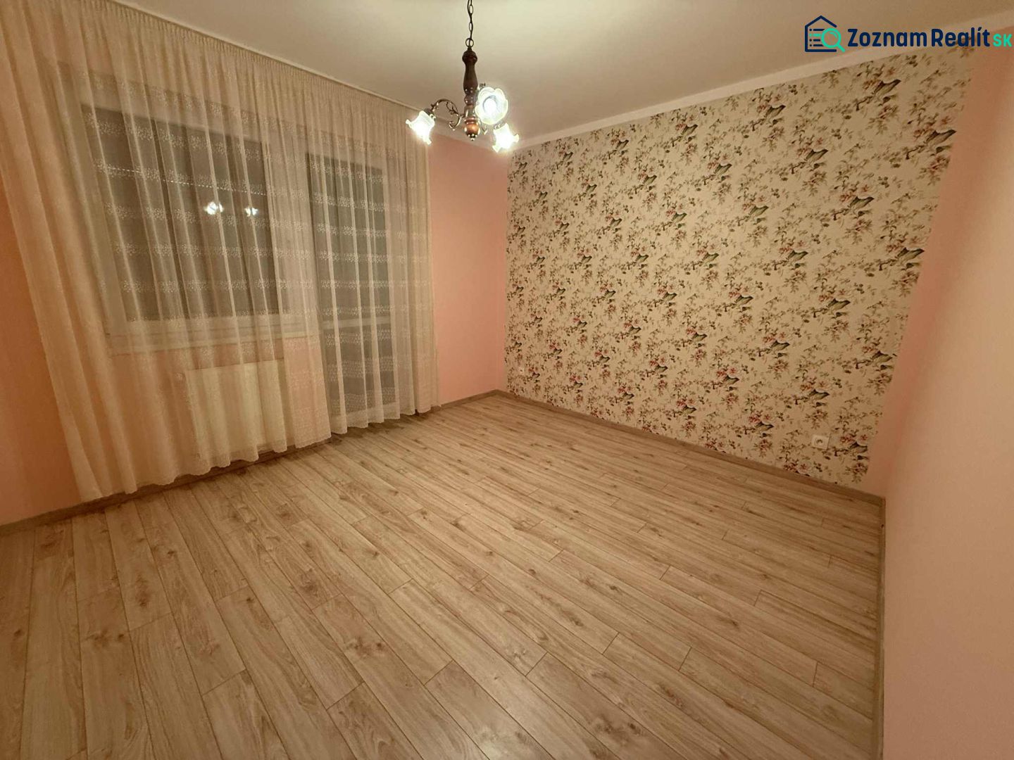 A room with patterned wallpaper, curtains, and a floor with a wooden decor in a three-room apartment.