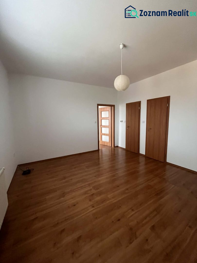 A room in a 3-room apartment with white walls and a floor with a wooden decor.