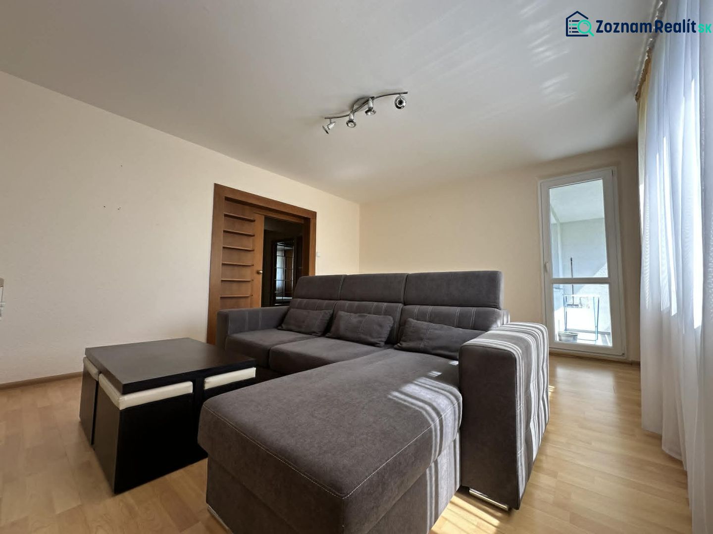 Living room in a 3-room apartment with a sofa and wooden decor flooring.