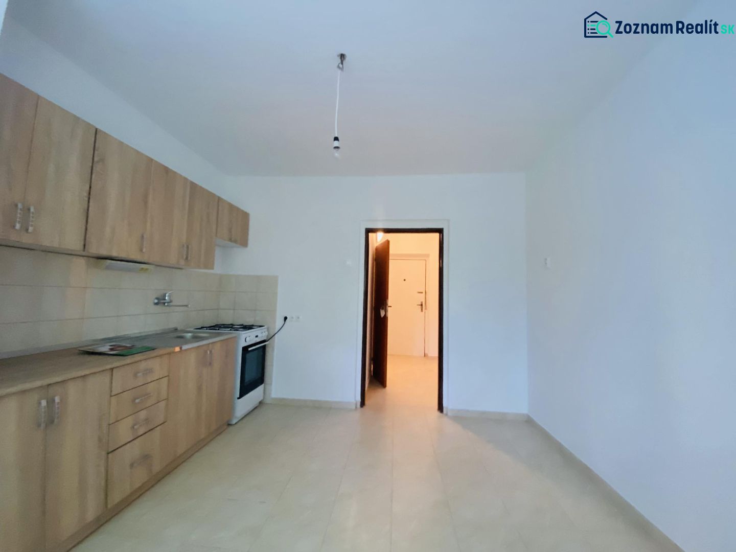 A kitchen in a one-room apartment with a kitchen unit and light walls.