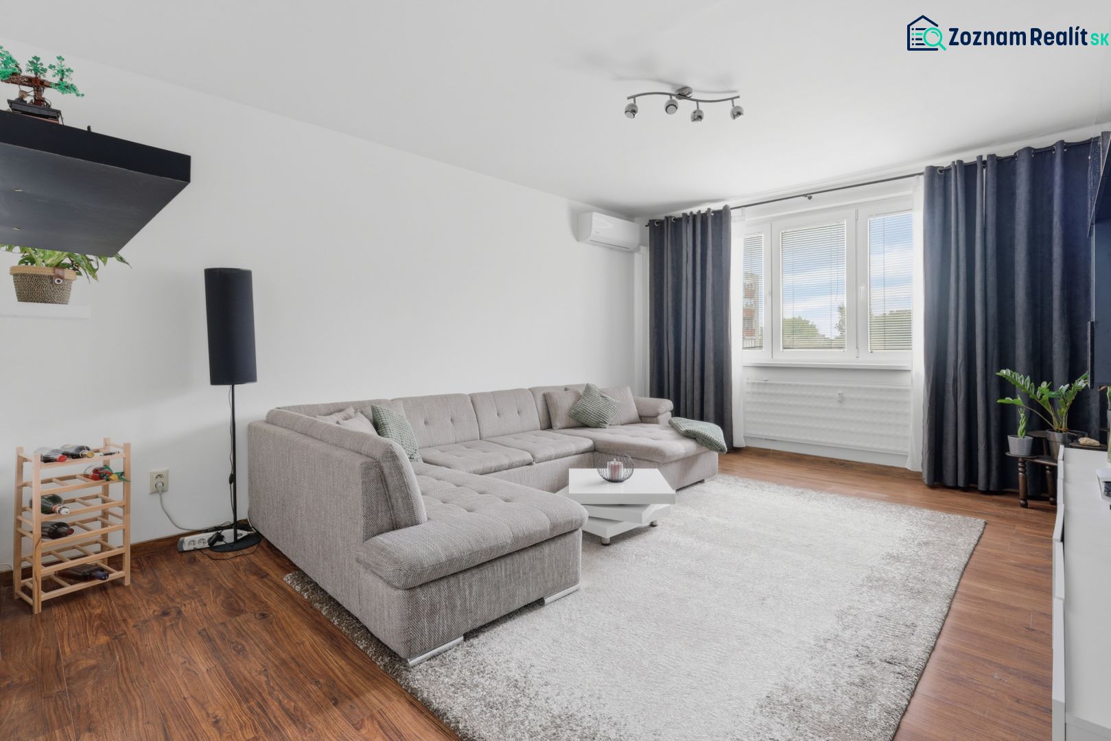 A bright living room with a corner sofa, wood-patterned flooring, 3-room apartment.