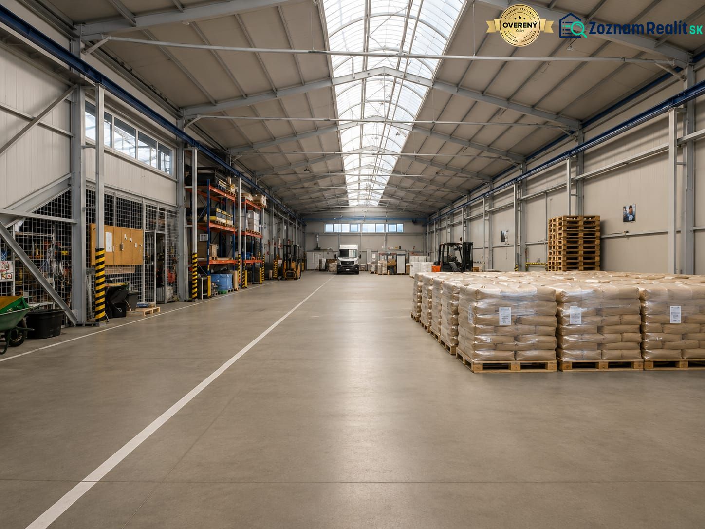 Interior of warehouses and halls with stacked pallets and a handling cart on the floor.