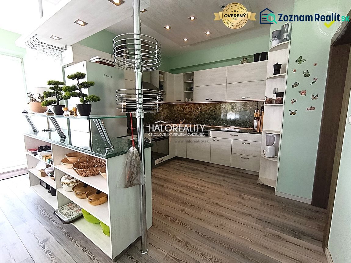 A kitchen in a 3-room apartment with a wooden decor floor and modern cabinet arrangement.