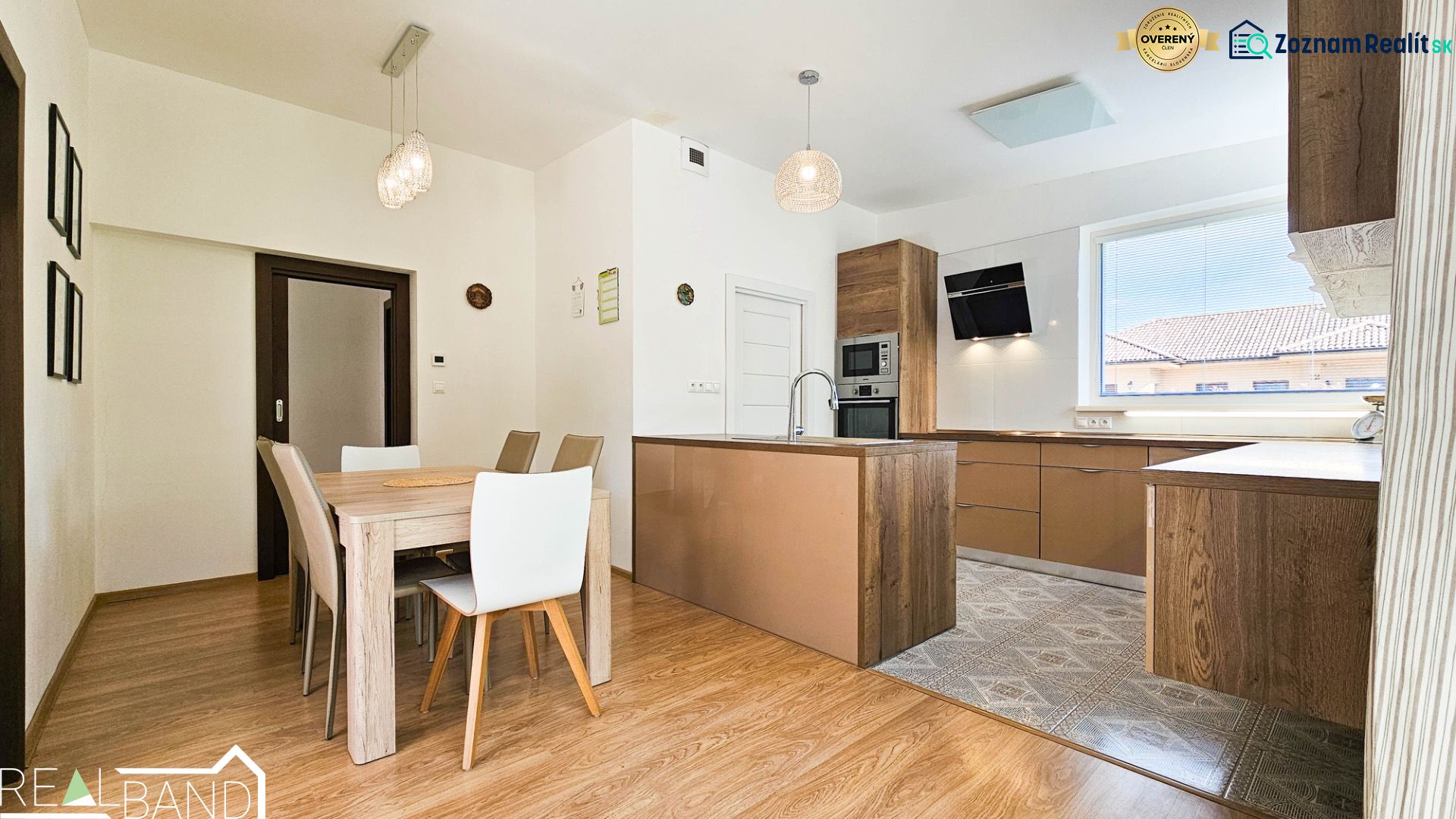Dining area and kitchen unit with wood-patterned flooring in a family house.