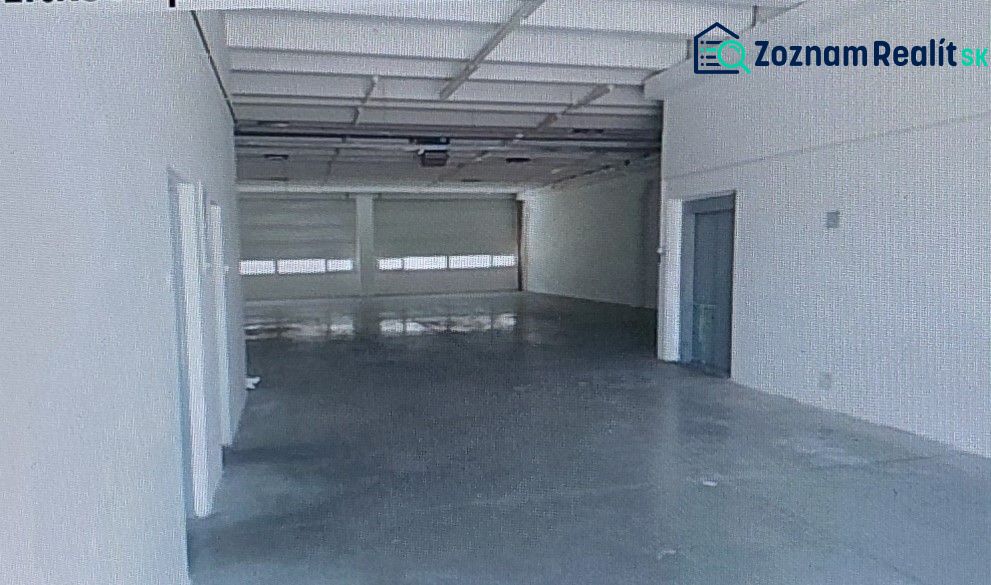 A spacious interior of a warehouse and hall with a concrete floor and white walls.