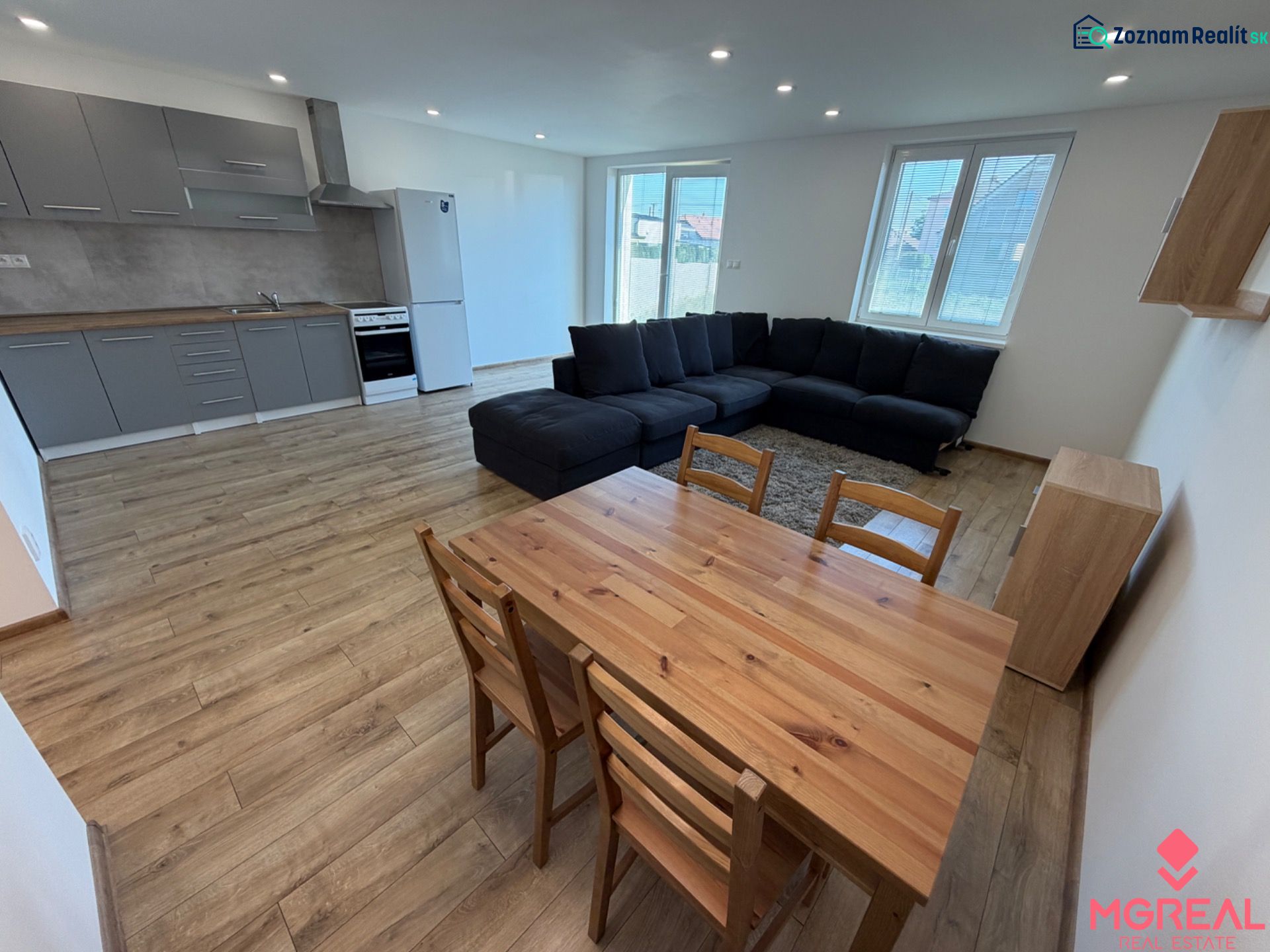 Living room with kitchen in a 3-room apartment with a wooden decor floor and a large sofa.