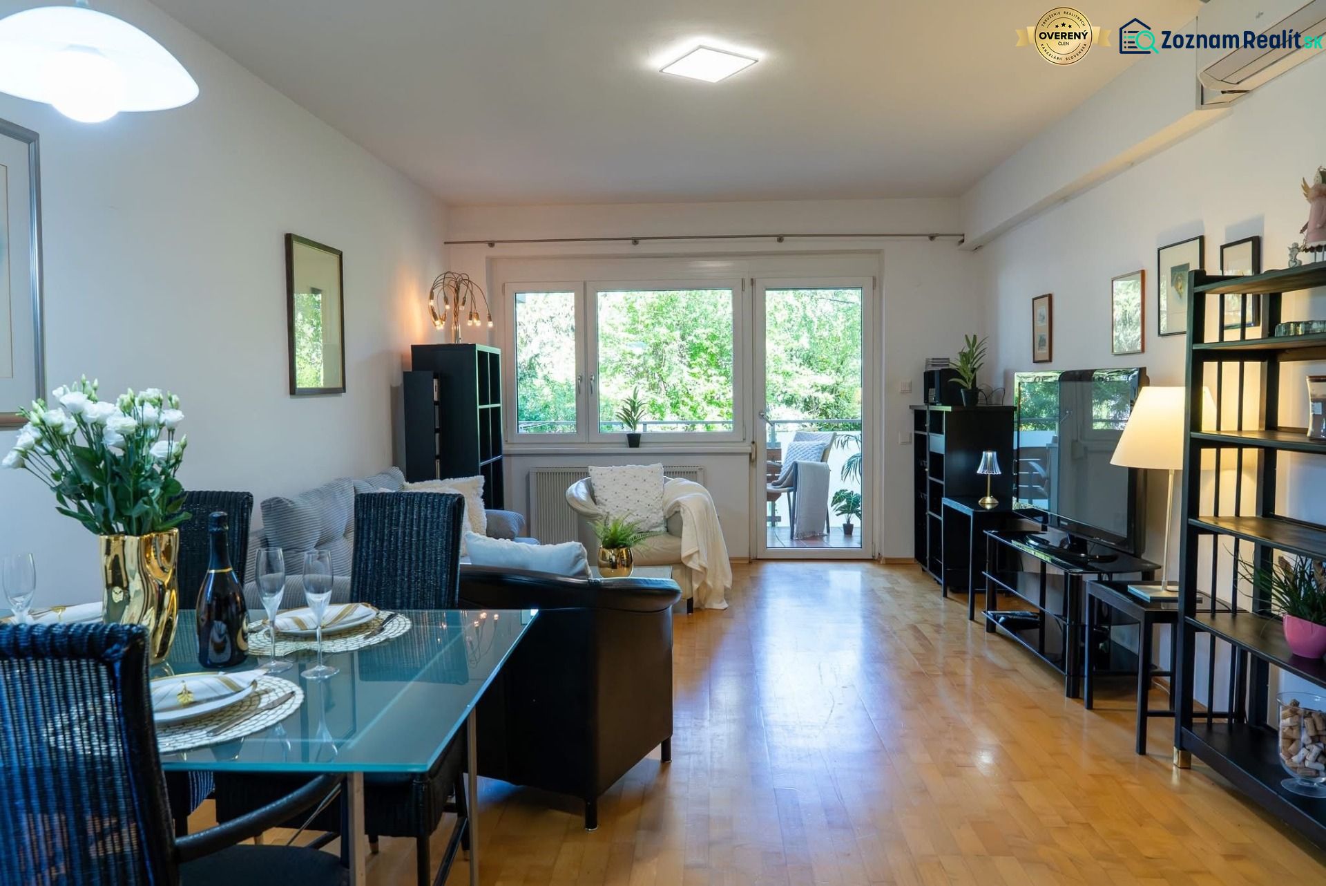 Living room of a three-room apartment with a wood-decor floor and a dining area.