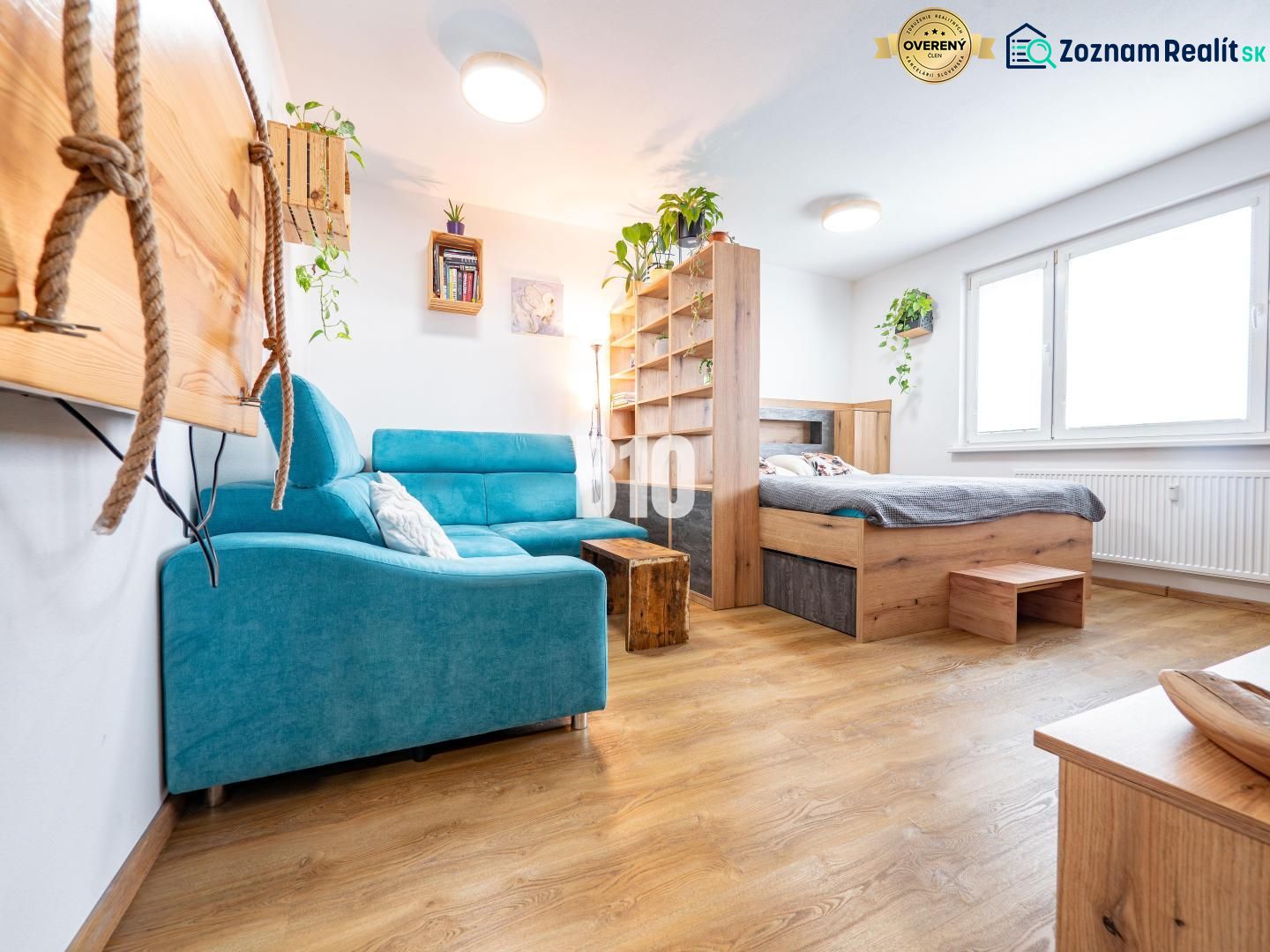 Bright 1-room apartment with wood-patterned flooring and a blue sofa.