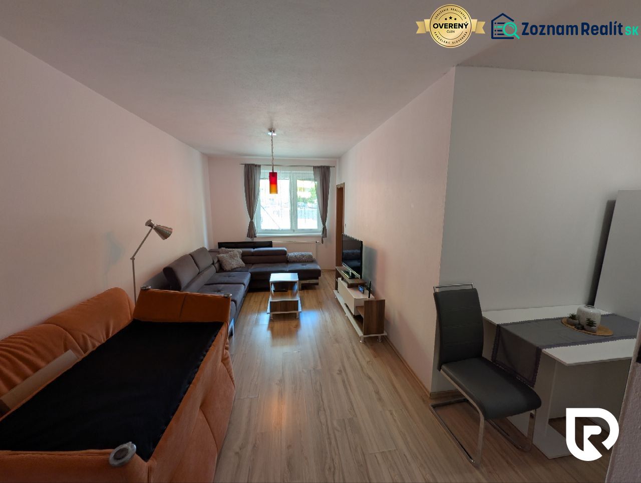 Living room in a two-room apartment with a wooden decor floor and comfortable seating.
