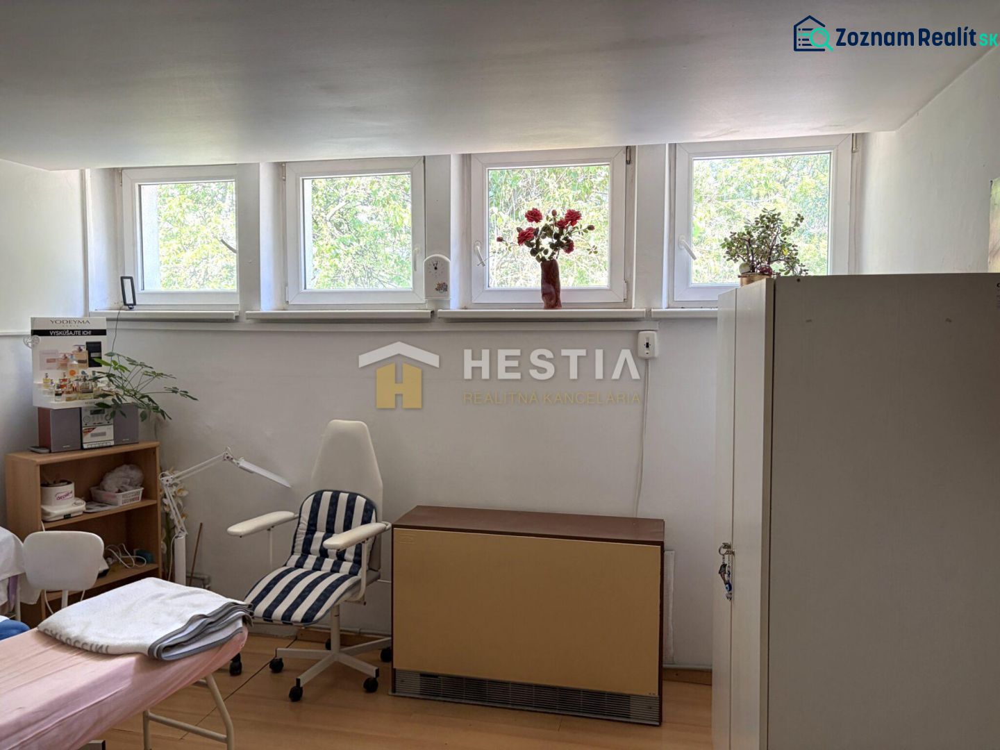 A room with a chair and a large window, commercial space with wood-patterned flooring.