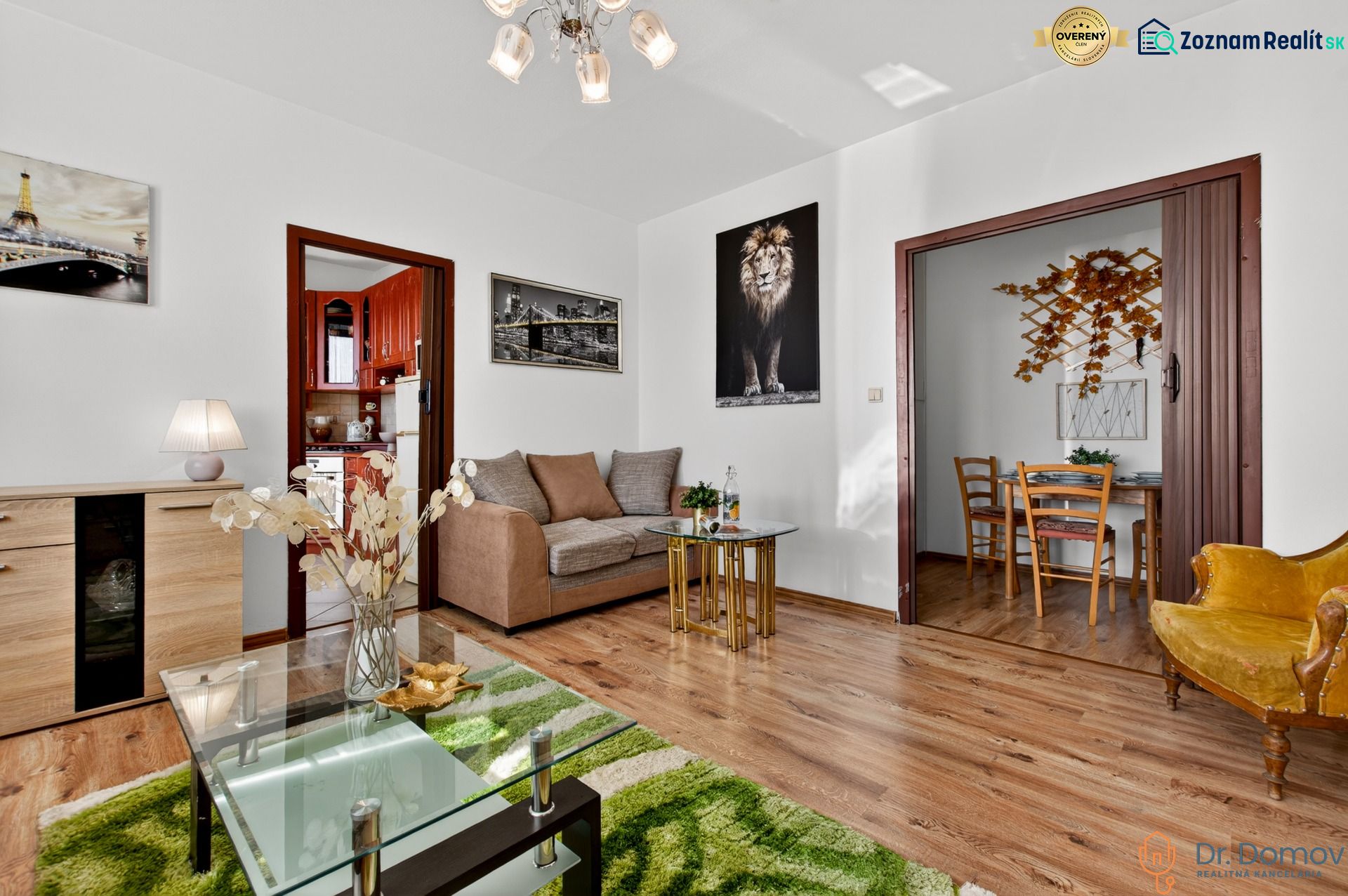 Living room in a two-room apartment with a sofa, table, and wooden decor flooring.