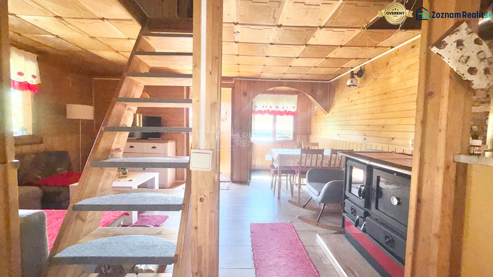 Interior of a cabin with wooden paneling, a kitchenette, and a staircase. Floor with a wood decor.