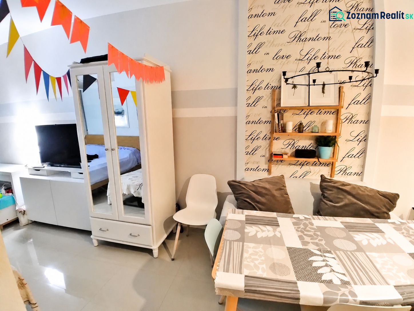 Storage cabinet, table with cushions, and decorative wall in a studio apartment.