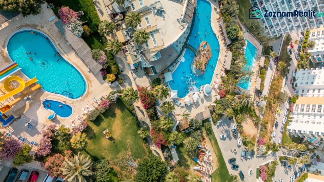 Aerial view of pools and gardens in the city of Iskele, surrounded by greenery and buildings.