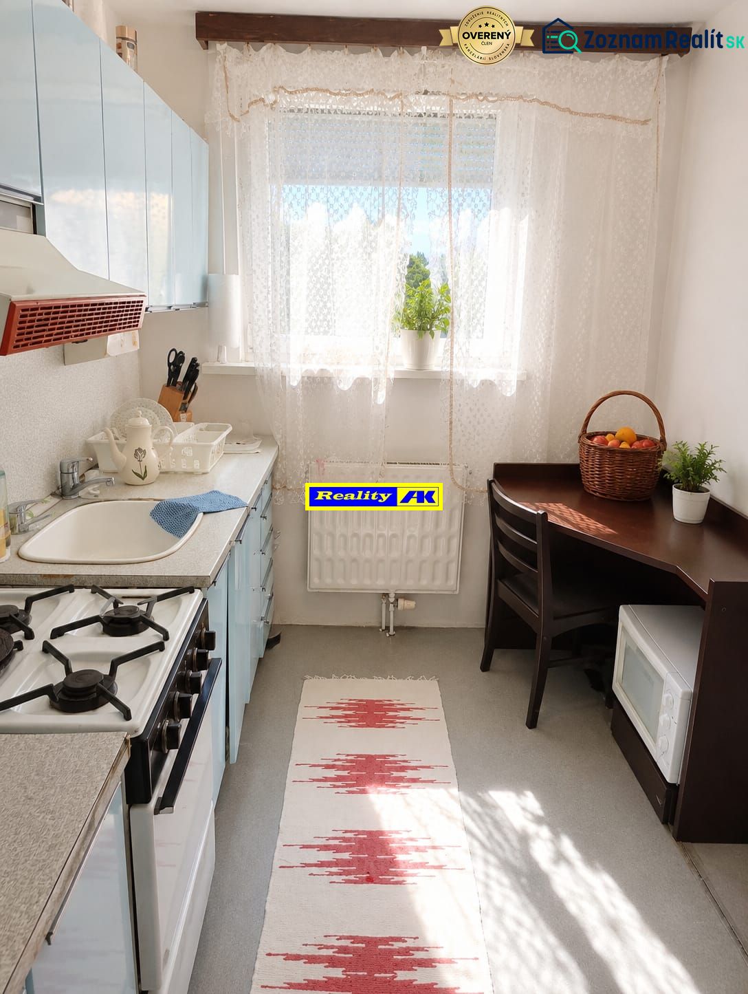 A kitchen in a 3-room apartment with a gas stove, dining table, and rug.