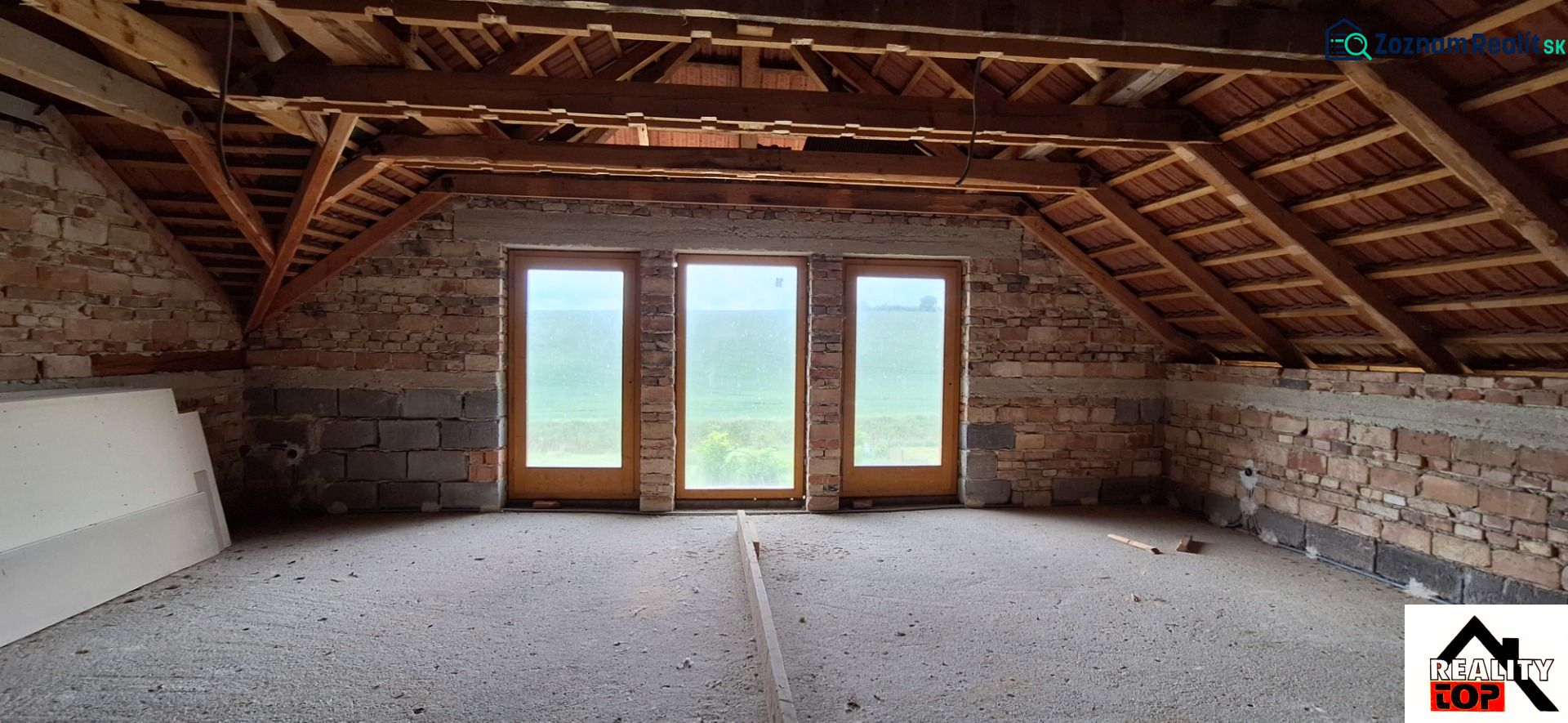 The attic of a family house with wooden beams and large glass doors.