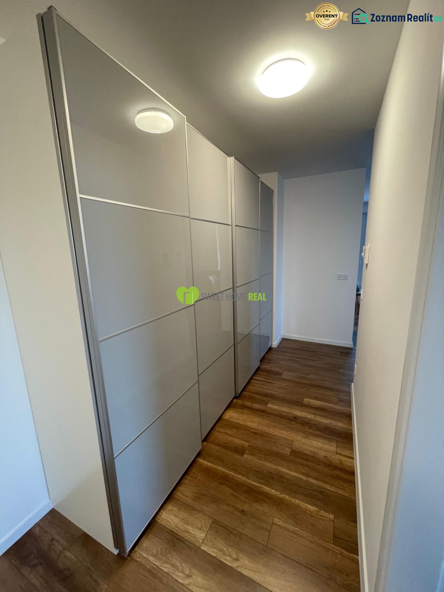 A hallway with a built-in wardrobe and flooring with a wood decor in a 2-room apartment.