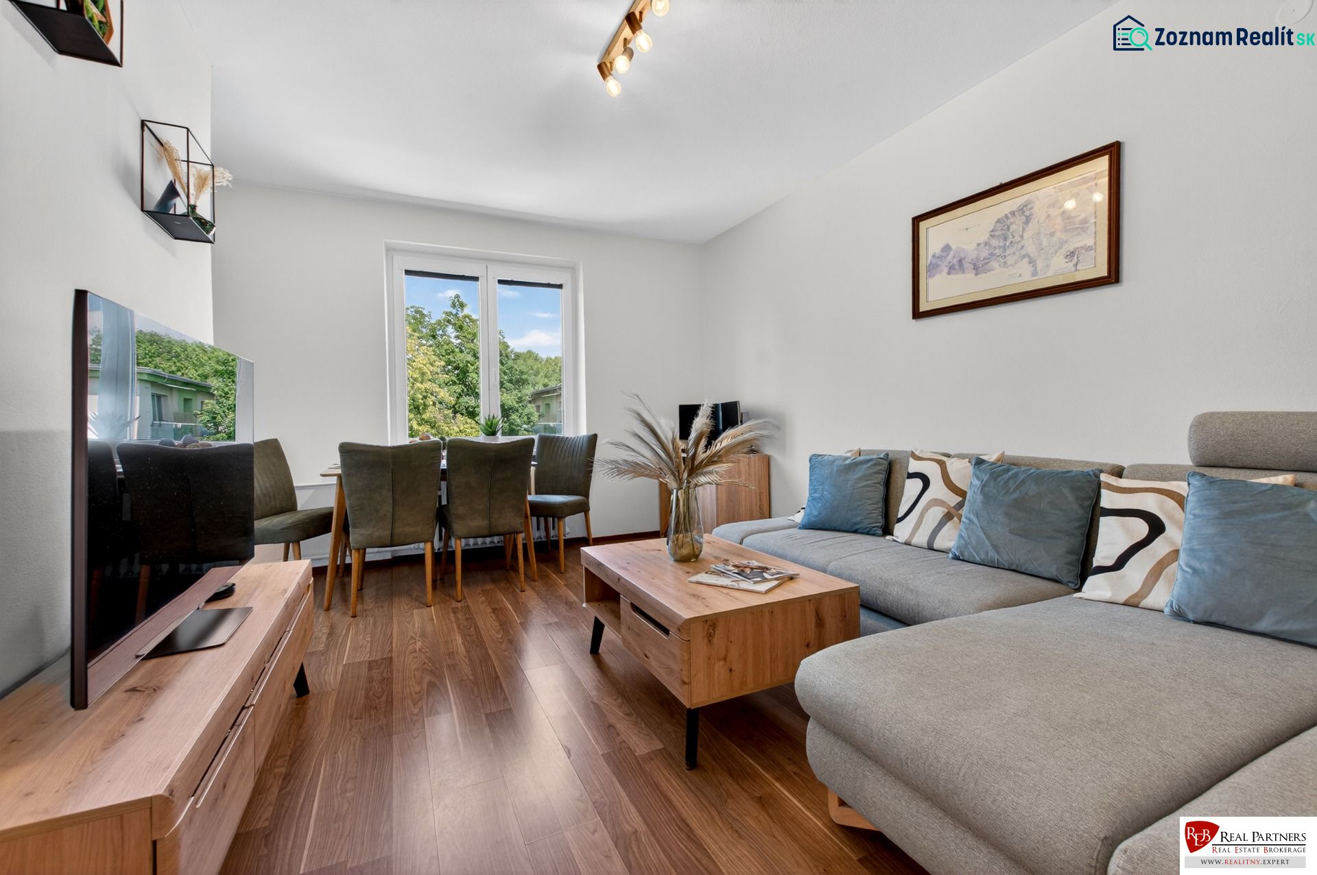 A bright living room in a three-room apartment with a wooden decor floor and a sofa.