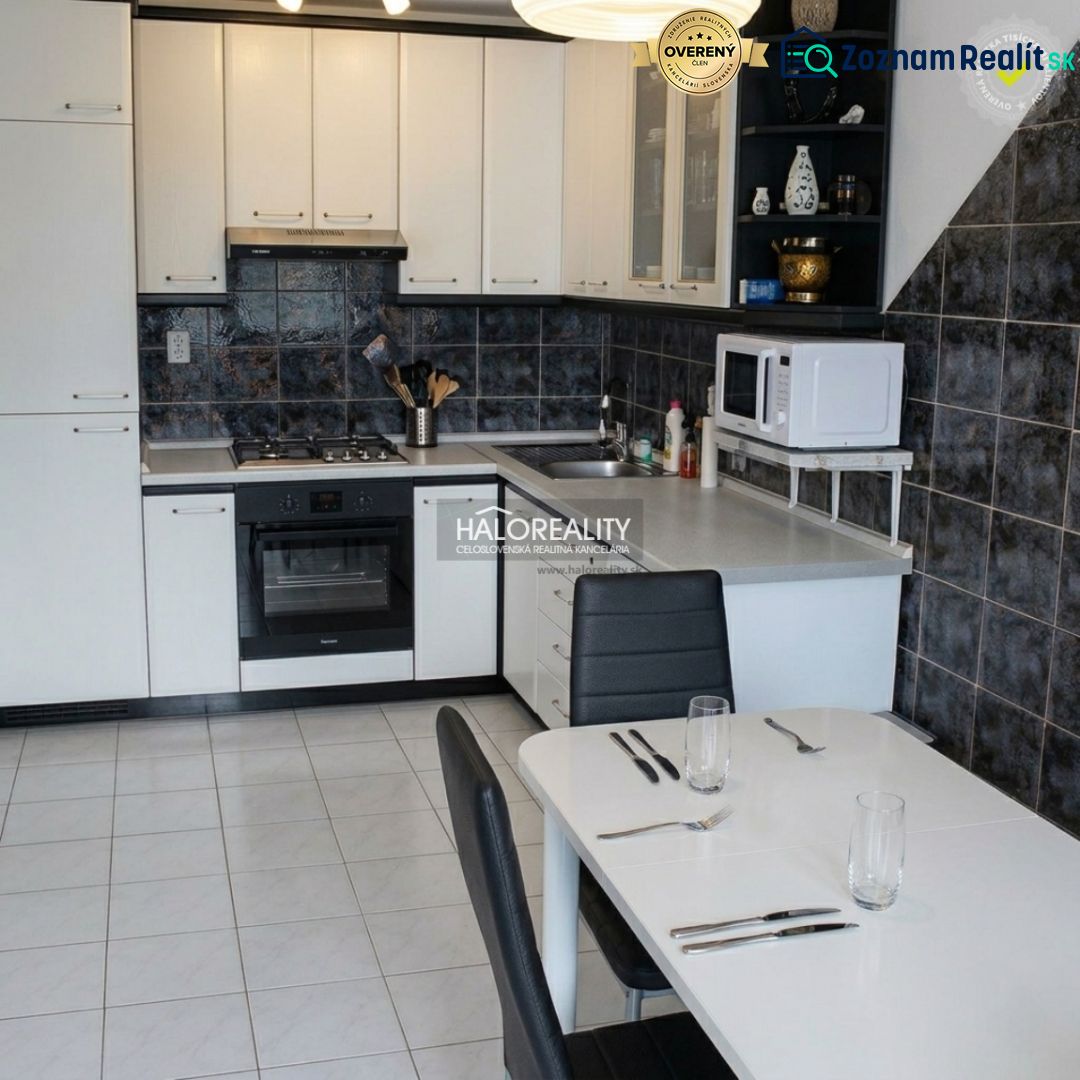 A kitchen with white cabinets in a 3-room apartment, a dining table, and ceramic tiles.