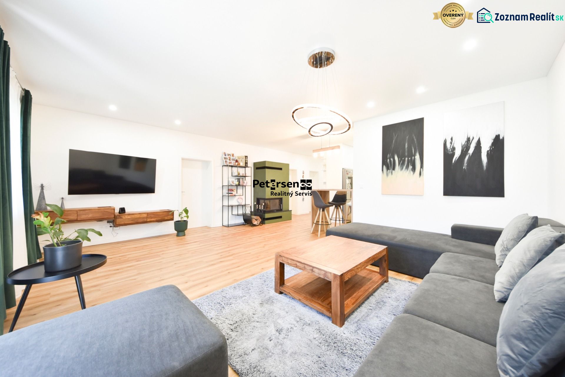 Living room in a family house with a large sofa, television, and wooden decor flooring.