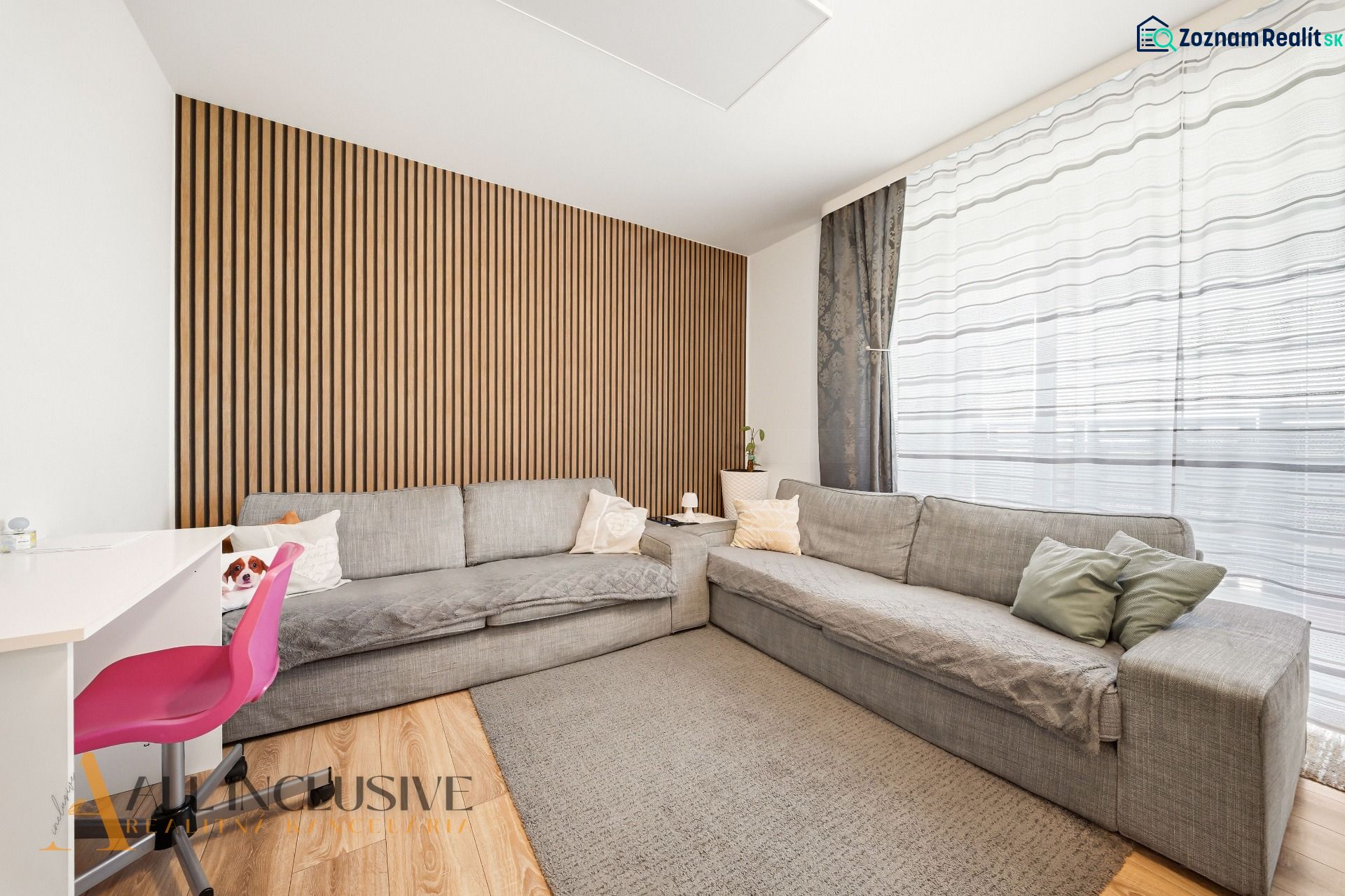 Living room in a three-room apartment with wooden decor and a gray sofa.