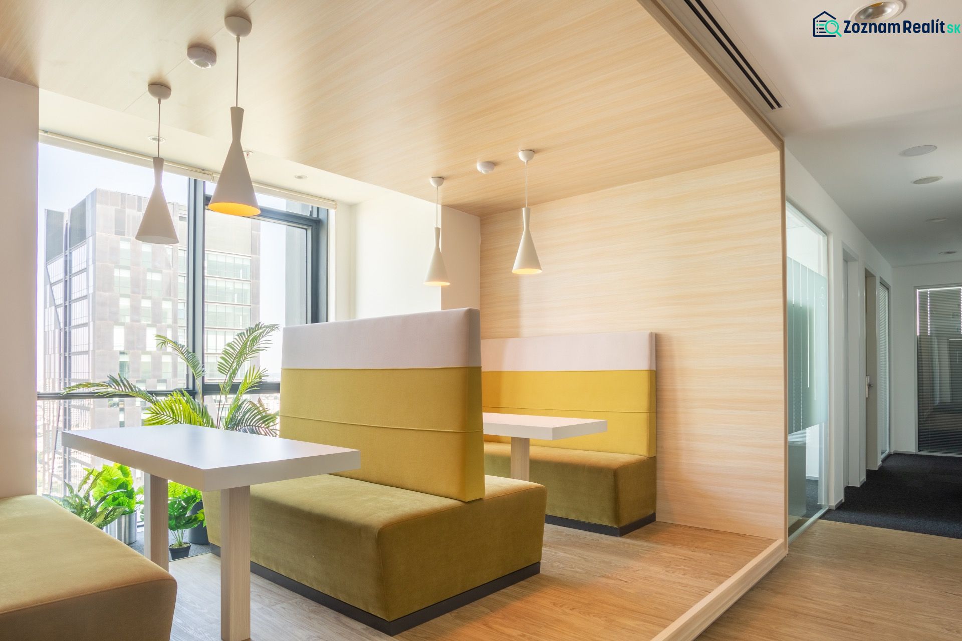 Dining in an office with a wooden floor decor and a view of a tall building.