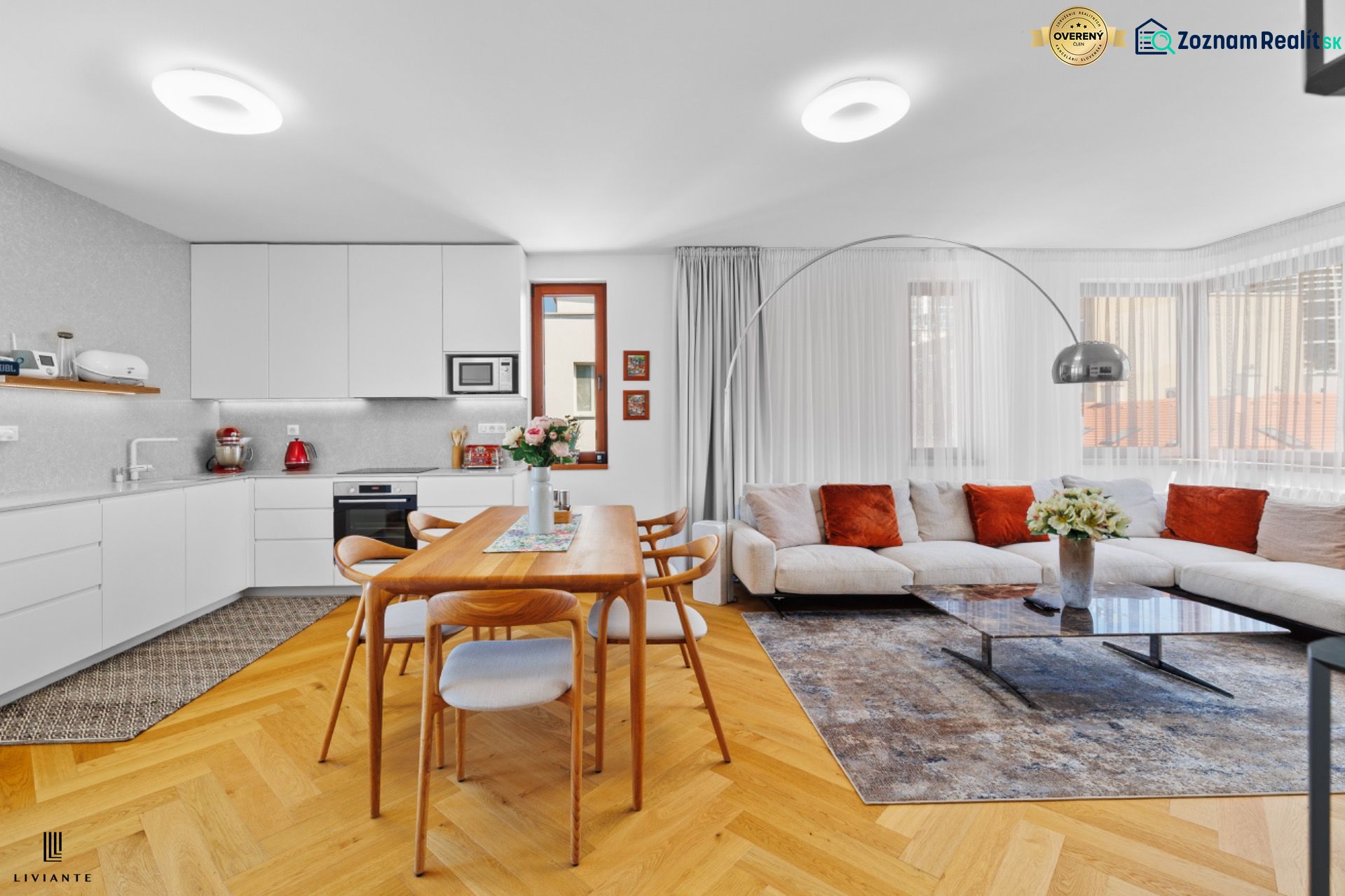 Bright kitchen and living room in a 4-room apartment with a wooden decor floor and a comfortable couch.