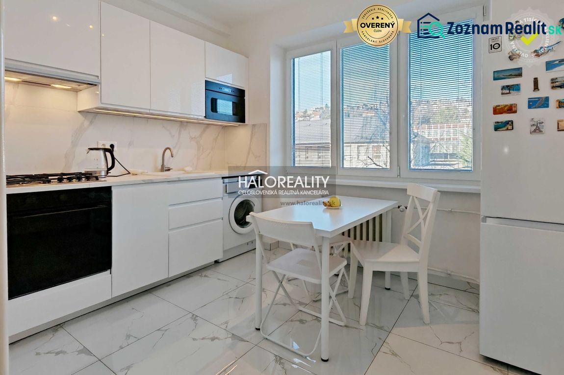 A bright kitchen in a 2-room apartment with white cabinets, a stove, and dining seating.