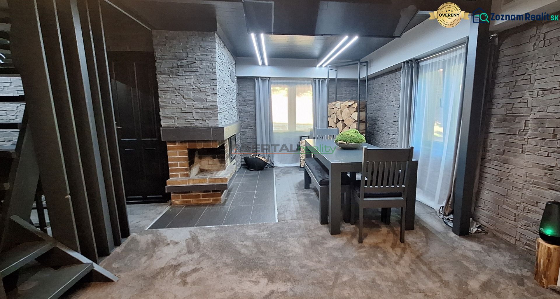 Living area in a cabin with stone cladding and a fireplace, complemented by a dining table.