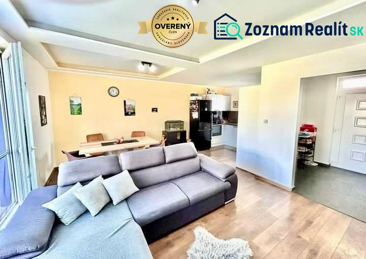 Living room in a family house with a sofa, dining table, and kitchen; floor with a wooden decor.