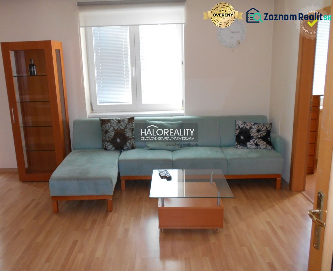 A living room with a blue sofa, a glass table, and a wooden decor floor in a three-room apartment.