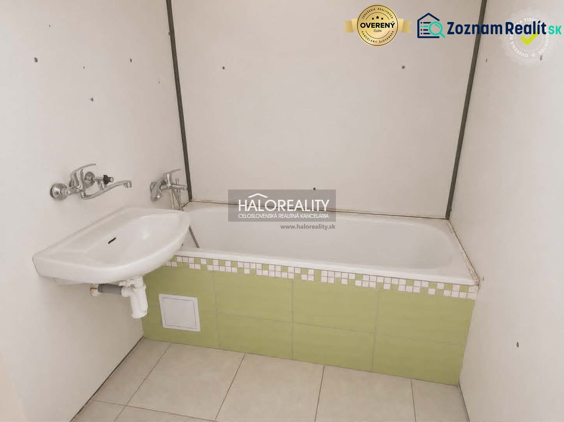 A bathroom in a studio apartment with a bathtub and a sink.
