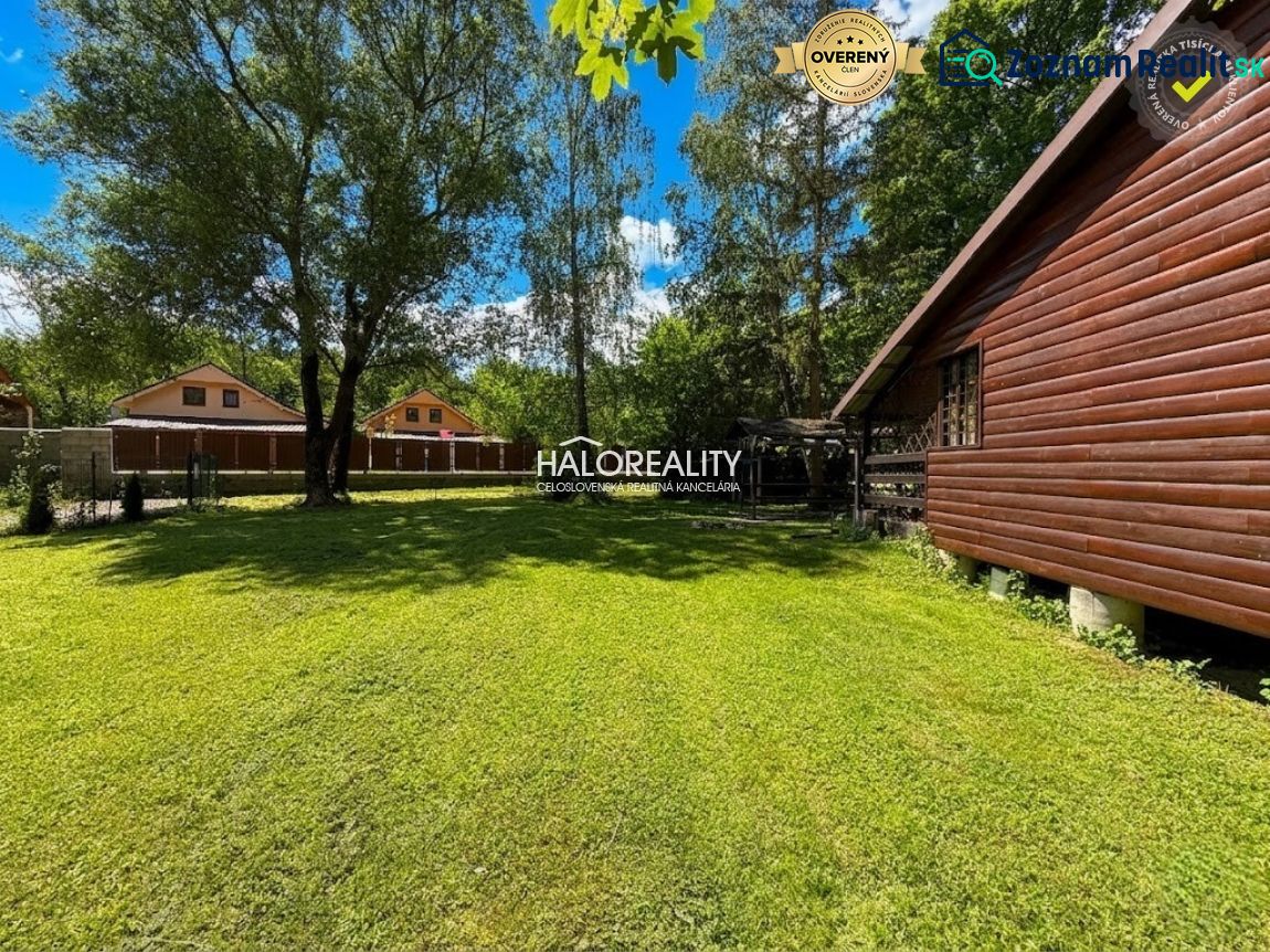 A wooden cottage in Prašice surrounded by a green lawn and trees.