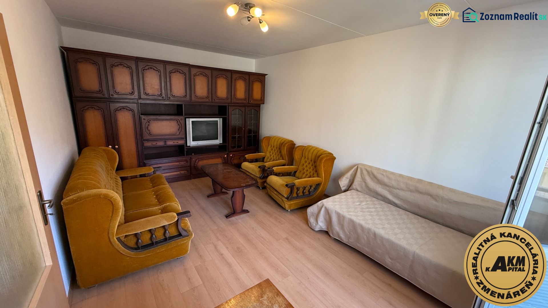 A living room with retro furniture and a wooden decor floor in a studio apartment.