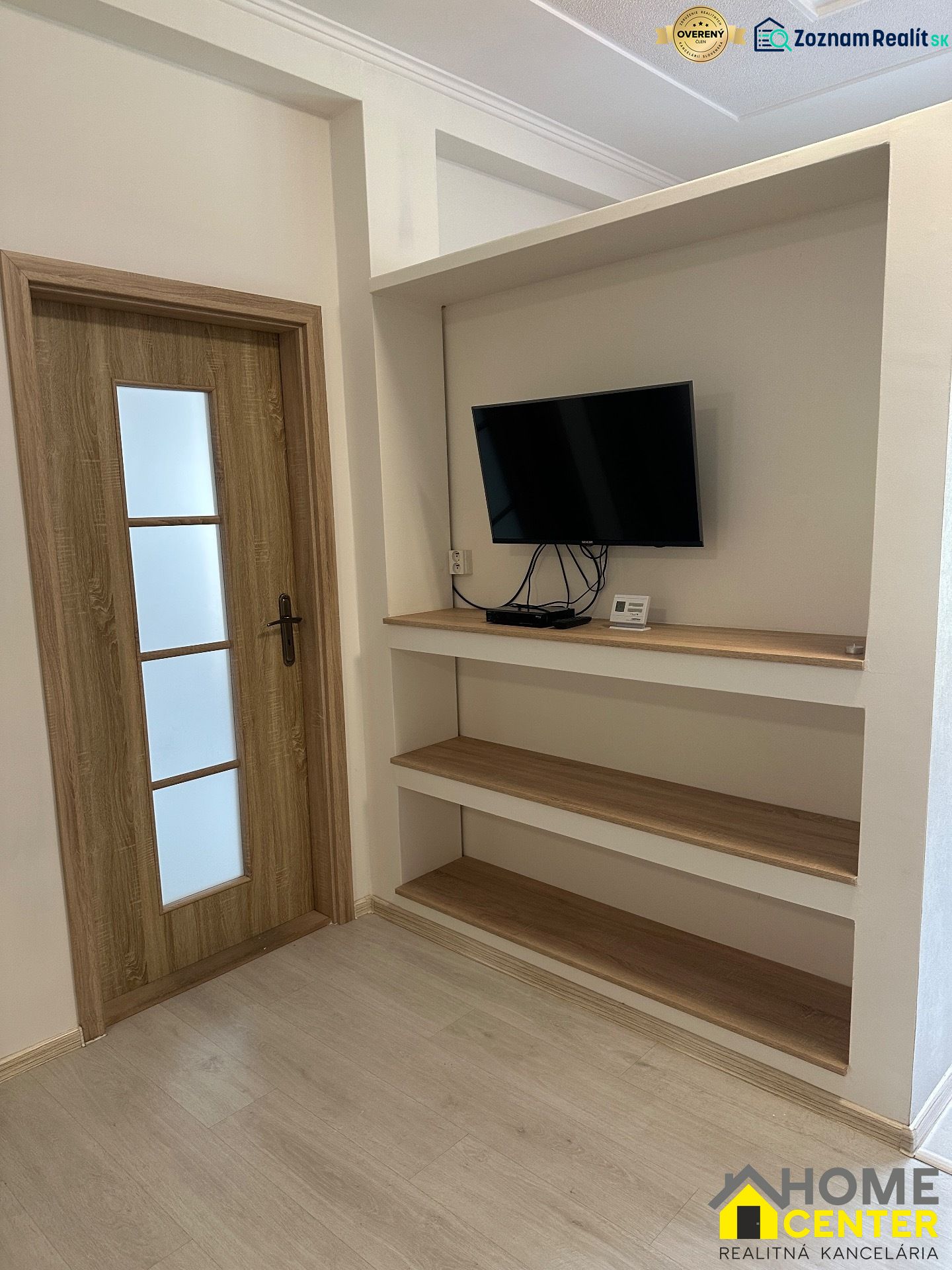 3-room apartment with a TV on the wall, shelves, and a floor with a wooden decor.