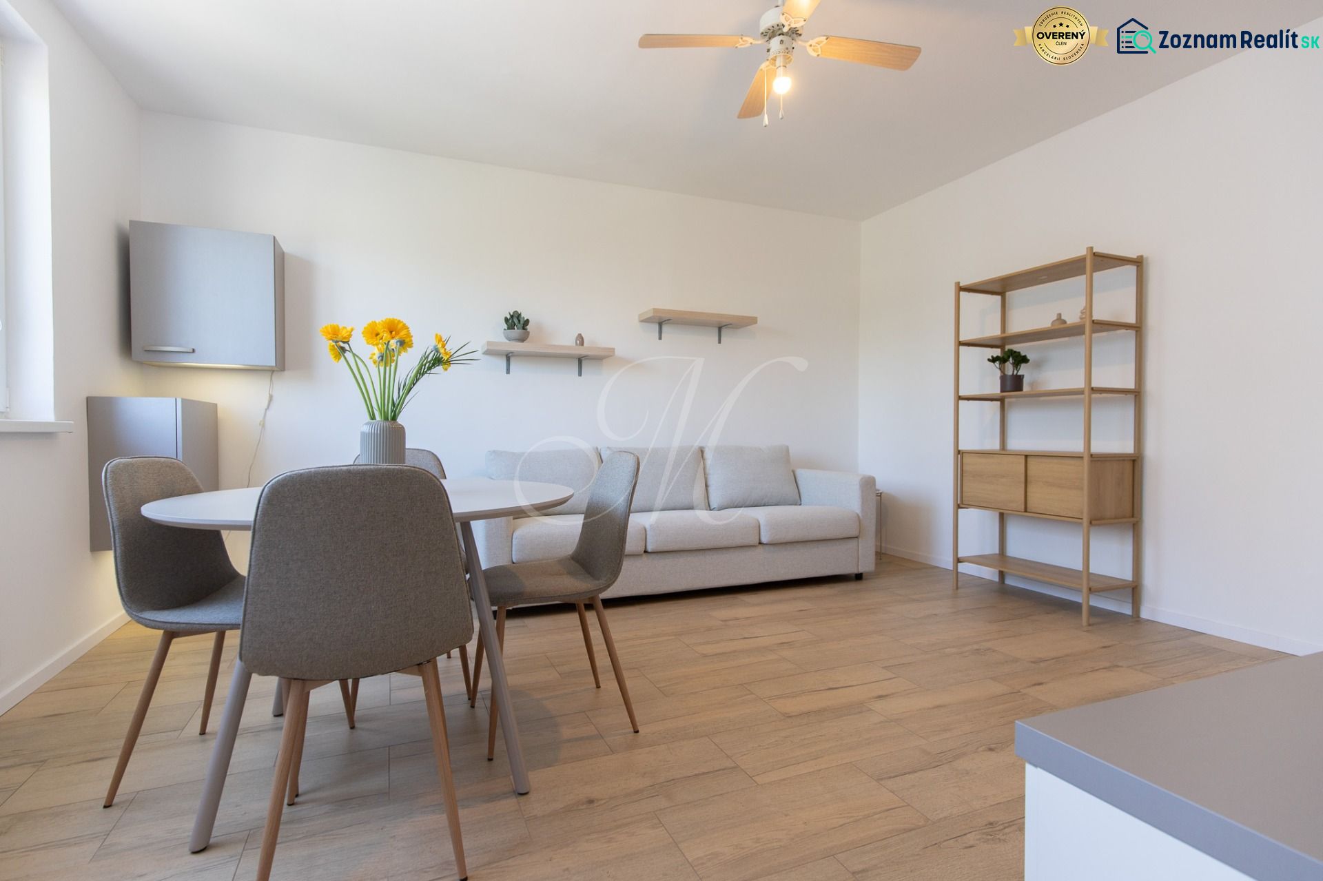Living room in a two-room apartment with a wooden decor floor and a dining table.