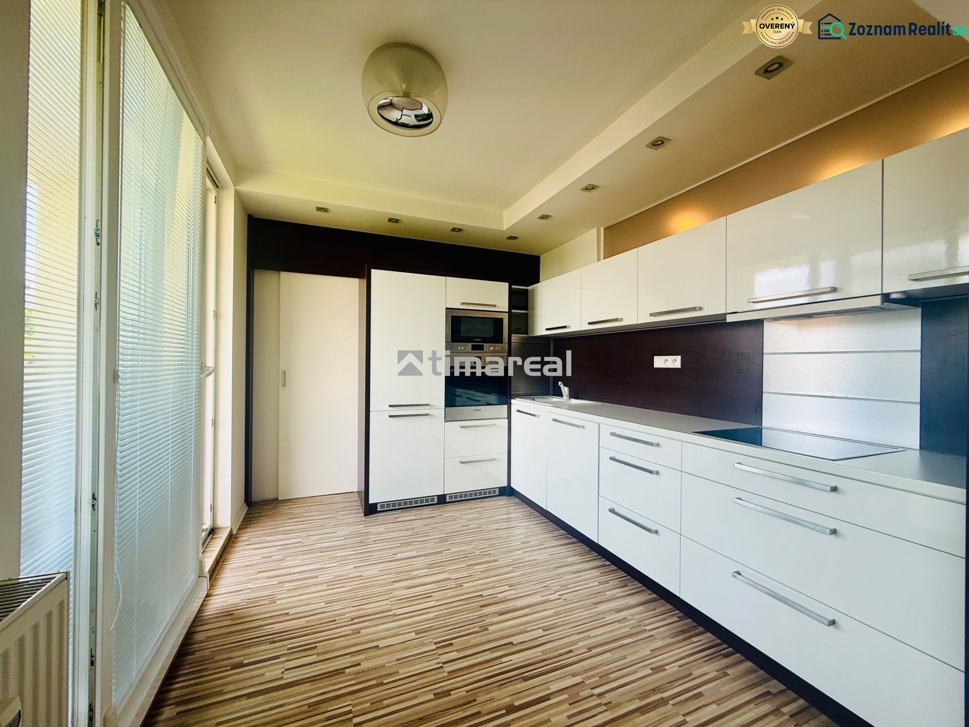 A kitchen in a 3-room apartment with white cabinets and a wooden decor floor.