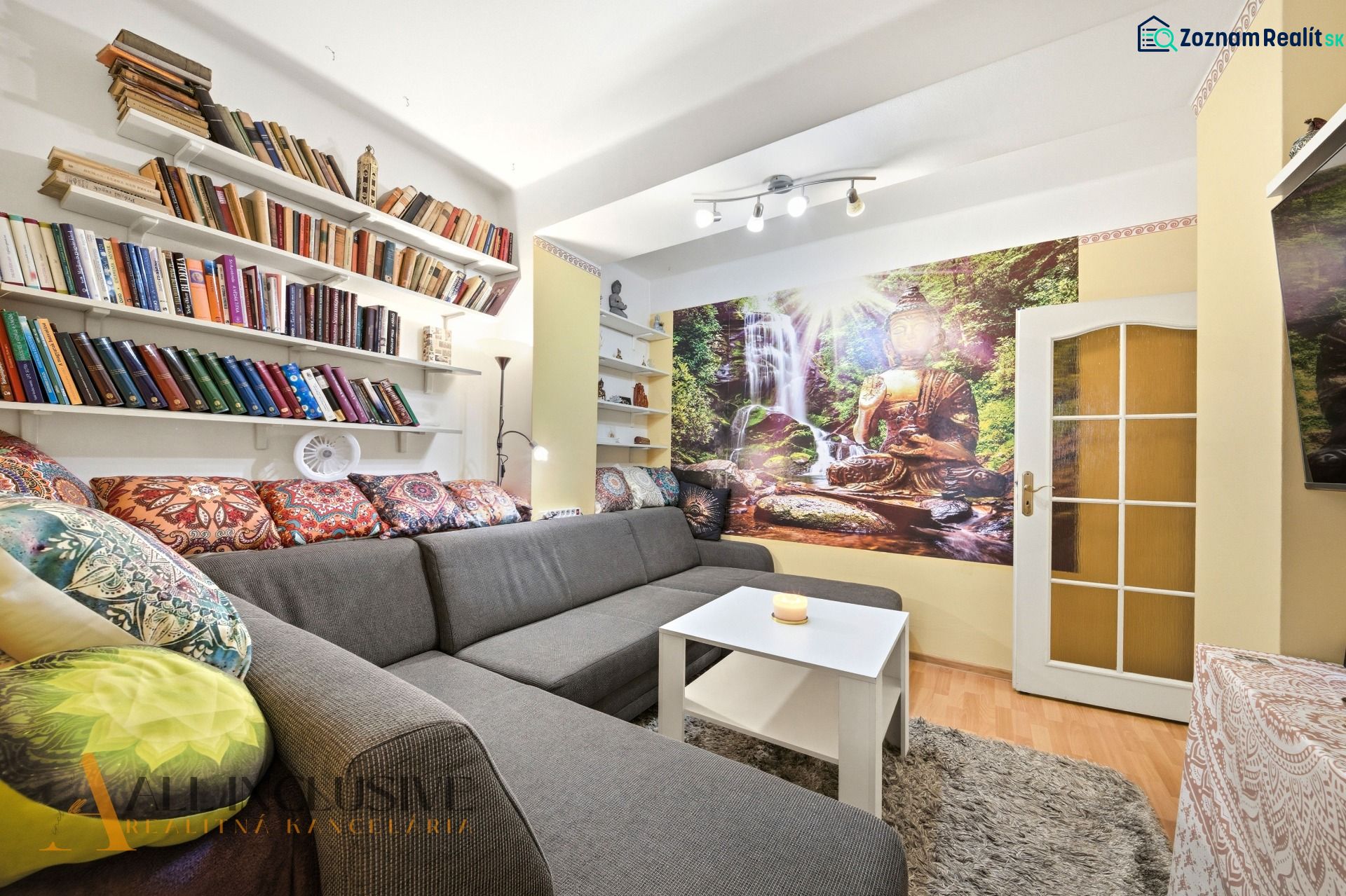 Living room in a 3-room apartment with colorful pillows, carpet, books, and an oriental photo wallpaper.